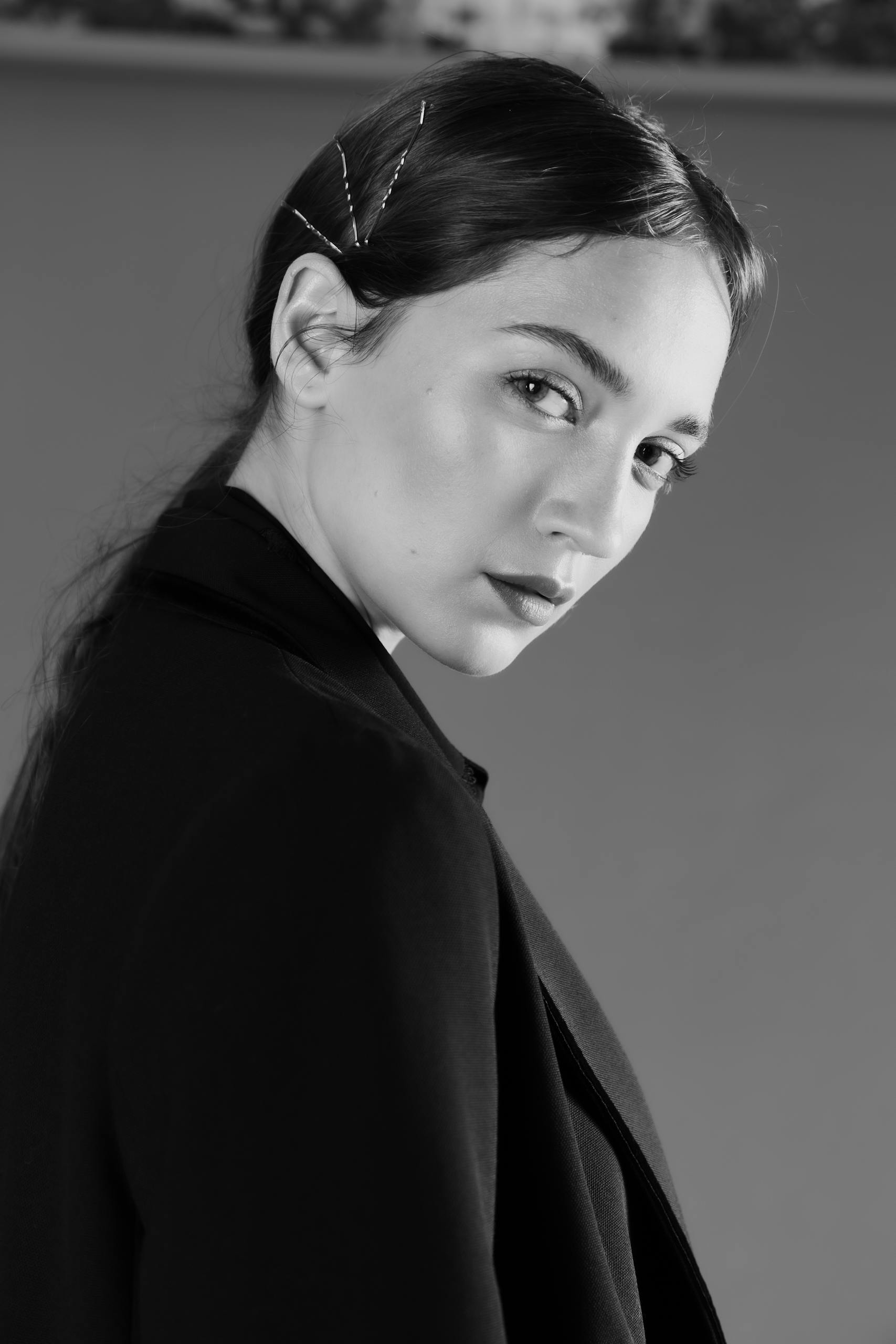 A woman with a black jacket and hair in a bun