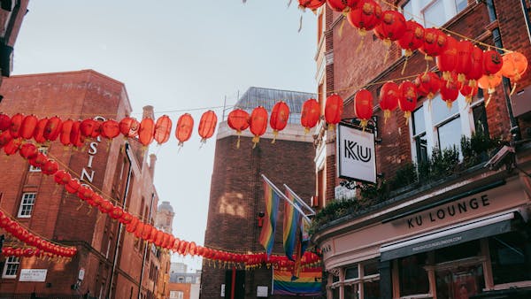 Colorful city street with red lanterns and rainbow flags during daylight.