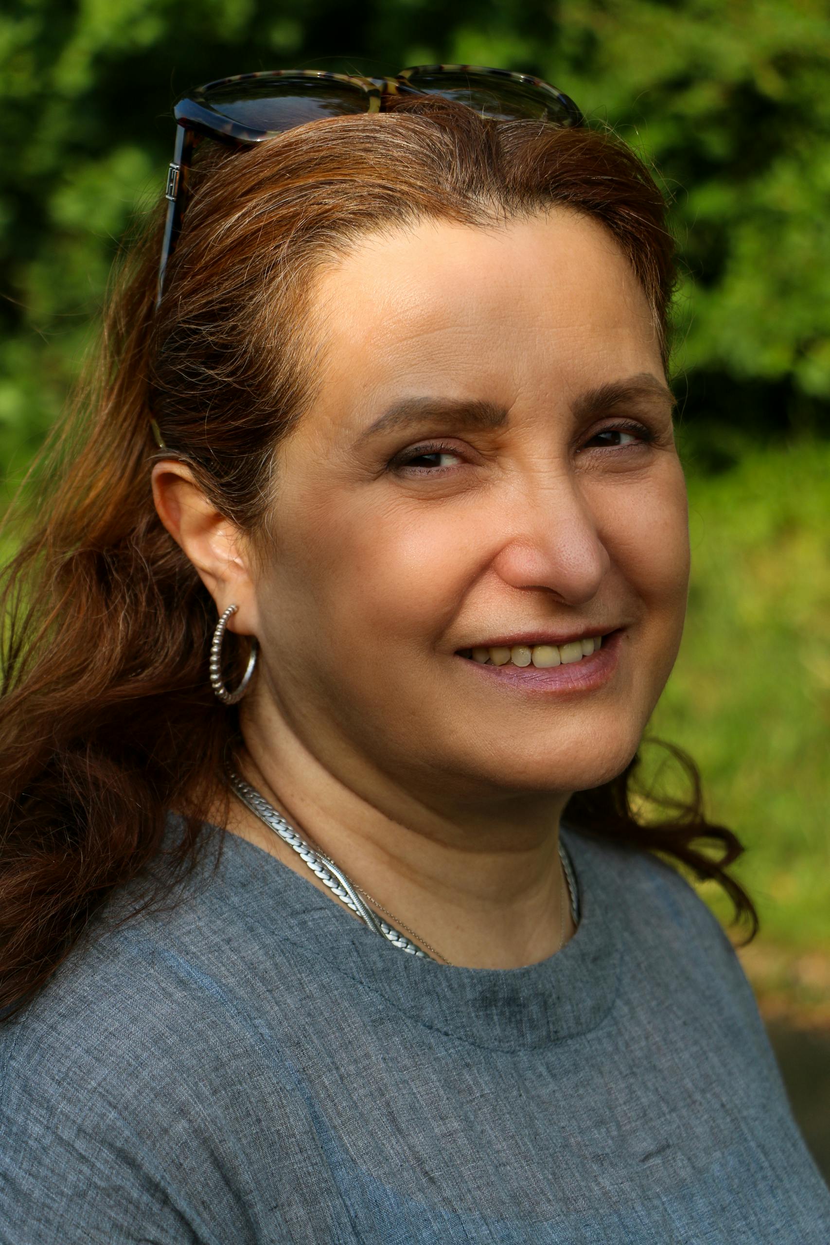 Portrait of a smiling woman in a sunny Brighton park. Summer vibes and natural beauty.